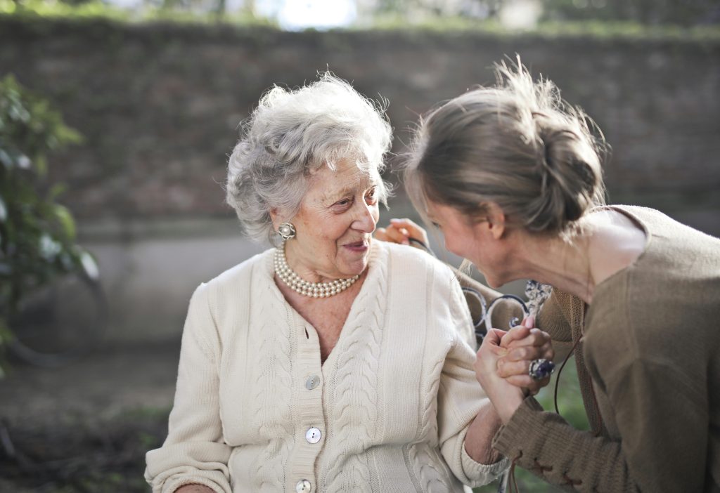Why Dehydration Poses Serious Risks For Seniors Joyful interaction between an elderly woman and her granddaughter in a sunny outdoor setting.